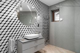 Łazienka z drewnopodobną posadzką i tapetą geometryczną
