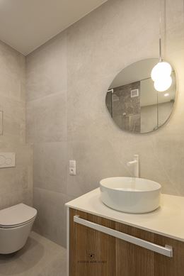 Mała, jasna łazienka z asymetrycznym lustrem