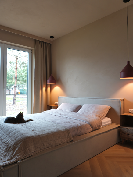 Beżowa sypialnia z szarym łóżkiem i bordowymi lampami