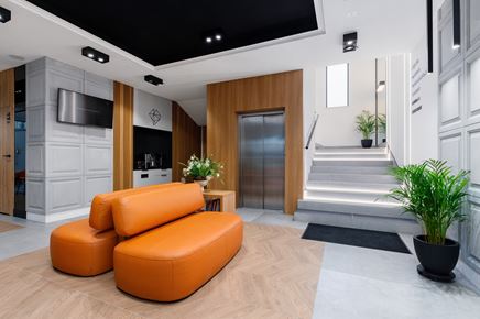 Poczekalnia z pomarańczowymi sofami i czarnym sufitem