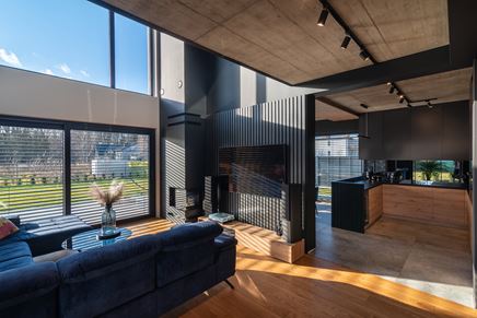 Czarne lamele na ścianie telewizyjnej w salonie z antresolą