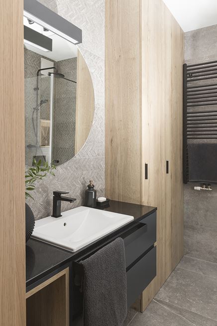 Czarne i drewniane szafki w szarej łazience