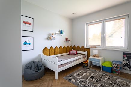 Pokój dziecka z białym łóżeczkiem i szarym dywanem