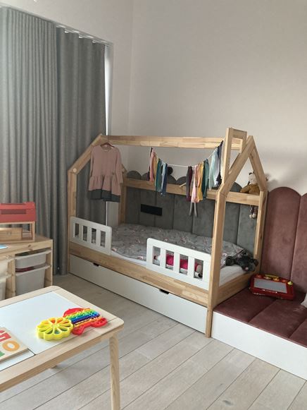 Łożko-domek z kolorową girlandą w pokoju dzieicęcym