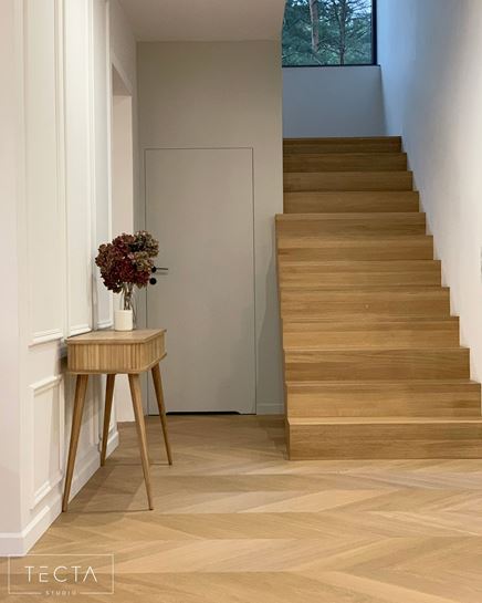 Minimalistyczny, bialy korytarz z drewnianymi schodami