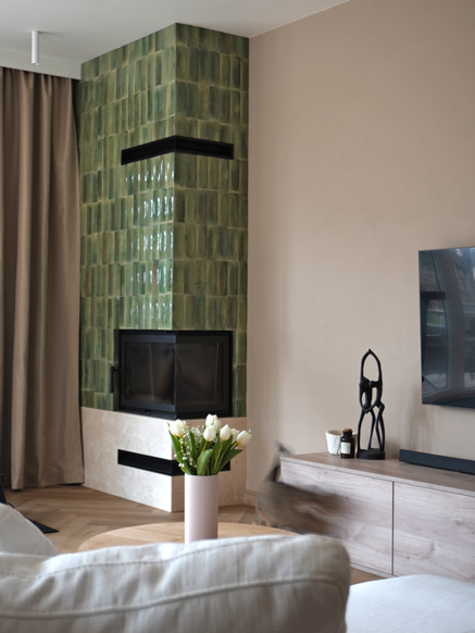 Salon z kominkiem wykończonym zielonymi kaflami