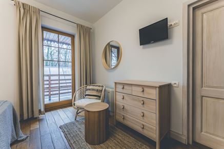Sypialnia w apartamencie z drewnianą komodą i fotelem z giętego drewna