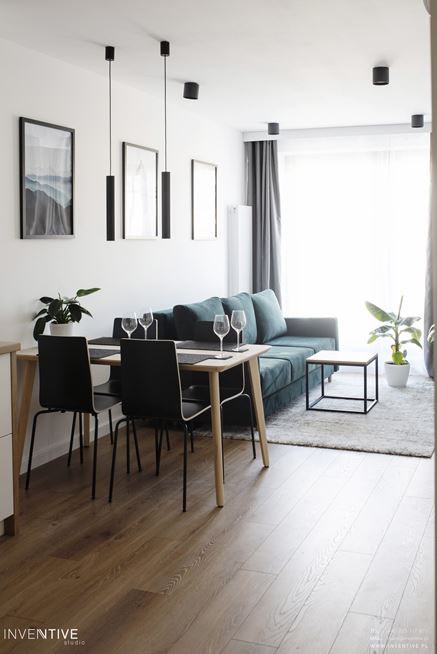 Salon z zieloną kanapą i prostokątnym, drewnianym stołem