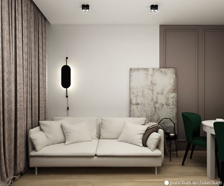 Krótka, biała kanapa i czarna lampa na ścianie