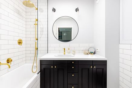 Biała łazienka z czarną szafką i złotymi elementami