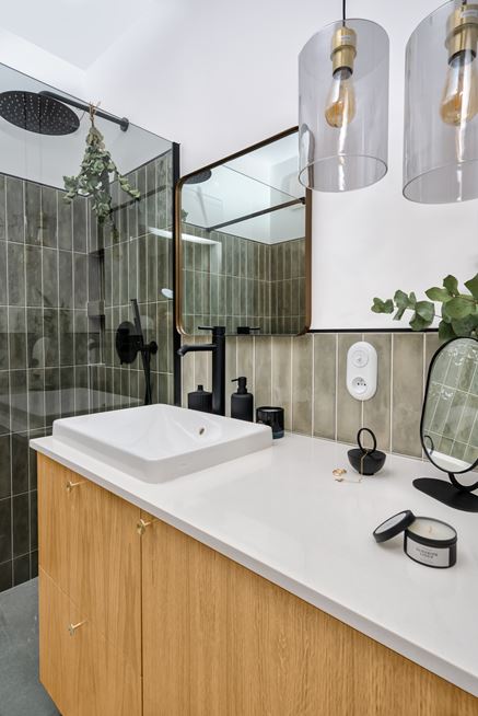 Biała łazienka z efektownymi, zielonymi kafelkami  pod prysznicem
