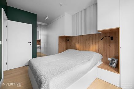 Sypialnia z zieloną ścianą i białymi szafami