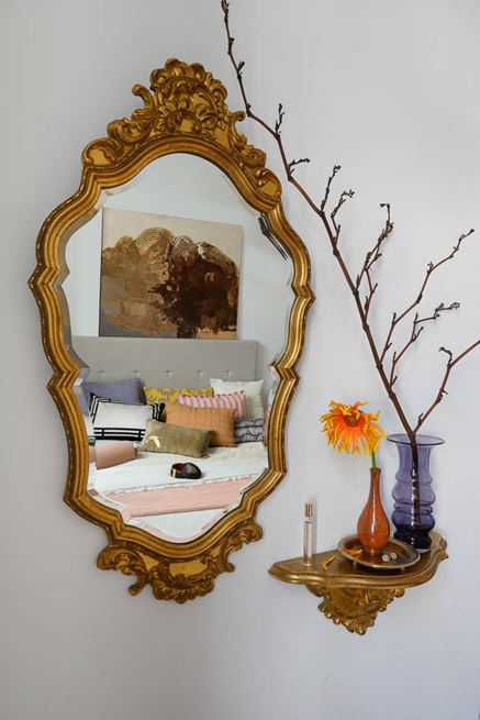 Złote lustro na białej ścianie sypialni