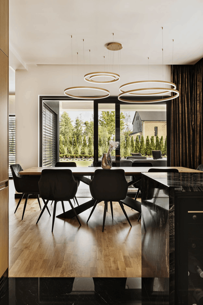 Drewniany stół na asymetrycznej nodze i czarne krzesła w jadalni, projekt AVO Architects
