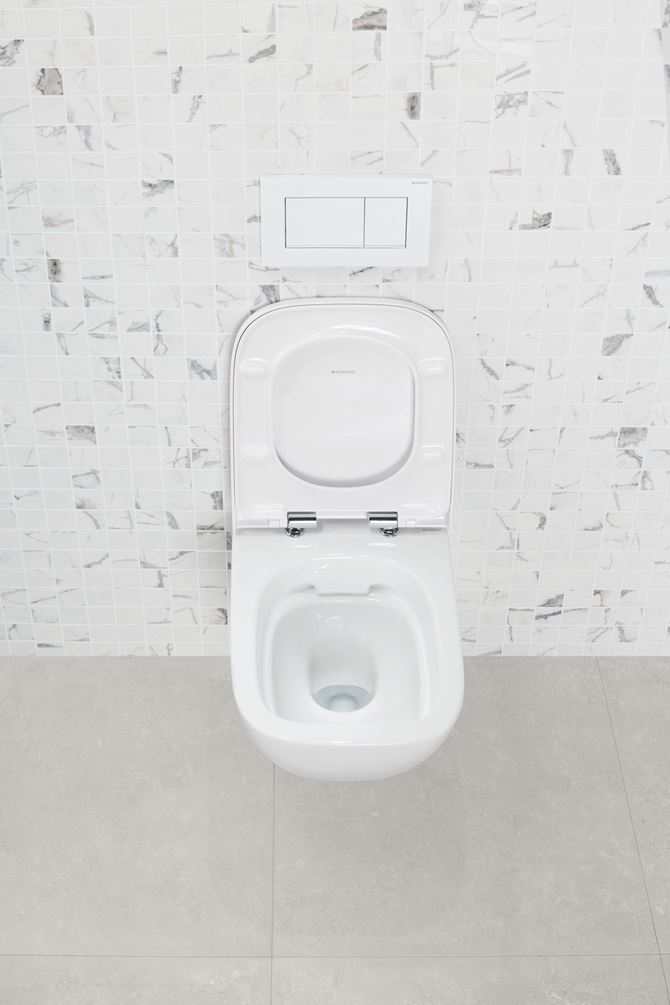 Bezrantowa muszla WC na tle szaro-białych płytek