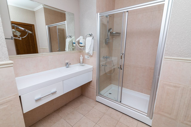 Hotelowa łazienka z prysznicem w odcieniach beżu.png