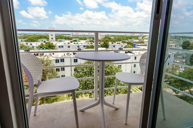 Niewielki balkon z przezroczystymi karierkami i białymi meblami