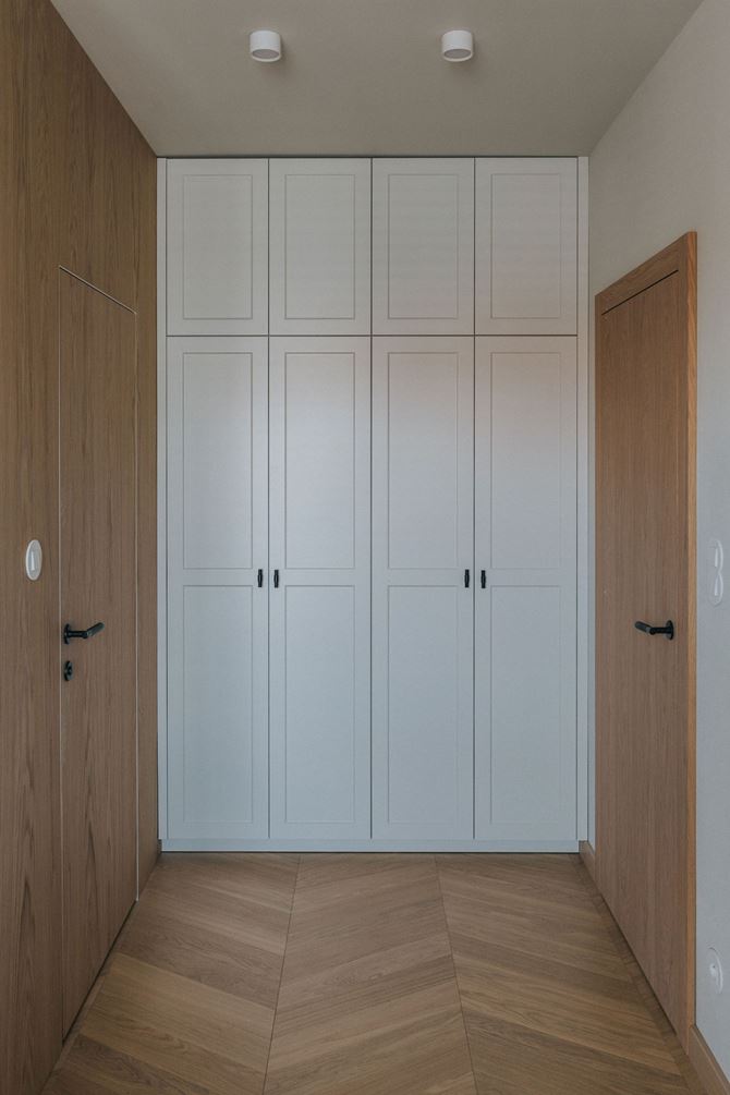 Ukryte drzwi fornirowane i białe szafy w zabudowie, projekt TYMA PROJEKT
