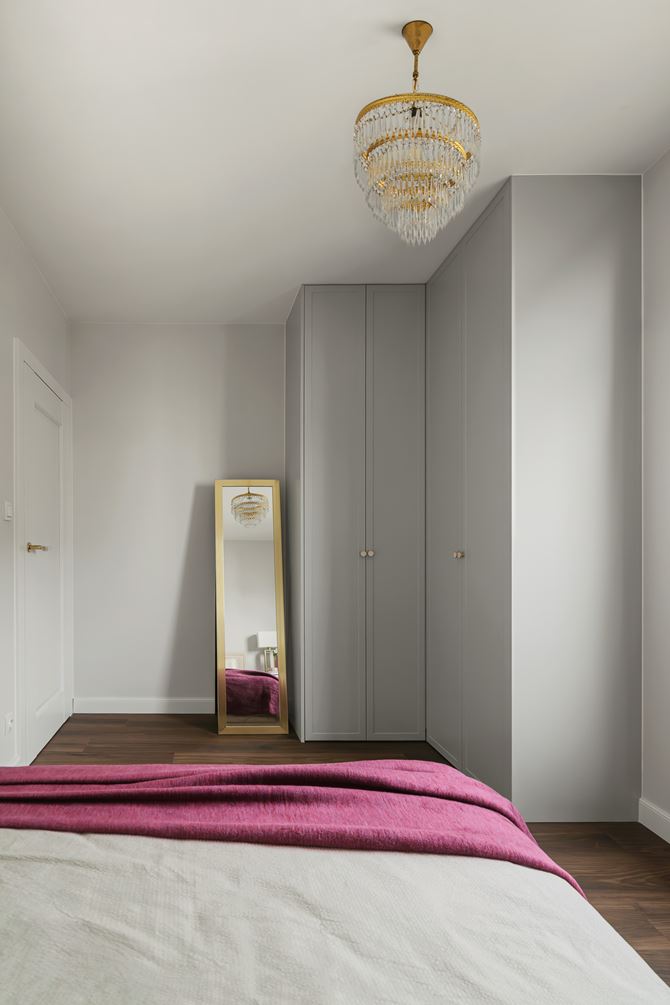 Biała sypialnia z szafką i żyrandolem, projekt Decoroom