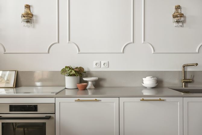 Detal ściany z białą sztukaterią nad blatem w kuchni, projekt Decoroom