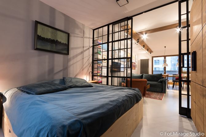 Loftowa sypialnia ze szklanymi drzwiami w małym mieszkaniu