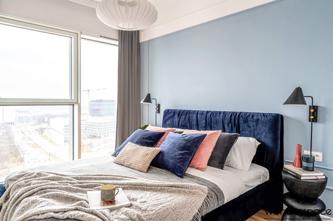 Sypialnia z niebieską ścianą i granatowym łóżkiem