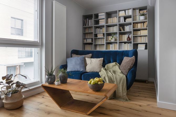 Biblioteczka i niebieska sofa w salonie