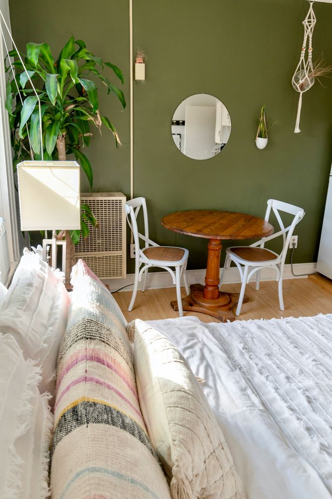 Zielona sypialnia boho ze stolikiem i krzesłami białymi