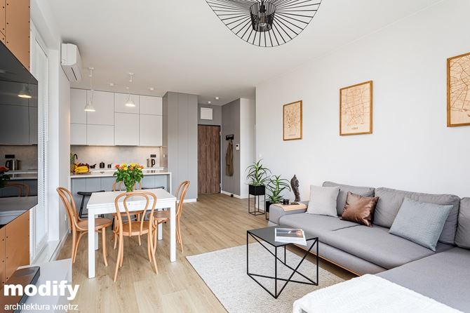 Biały salon z aneksem i szarym narożnikiem