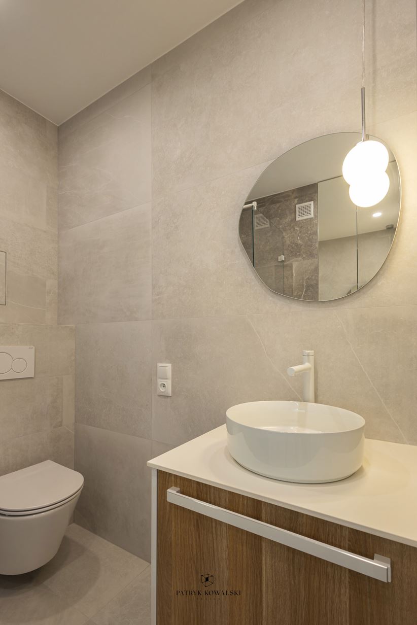 Mała, jasna łazienka z asymetrycznym lustrem