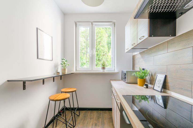 Wąska, jednorzędowa kuchnia z blatem barowym na ścianie