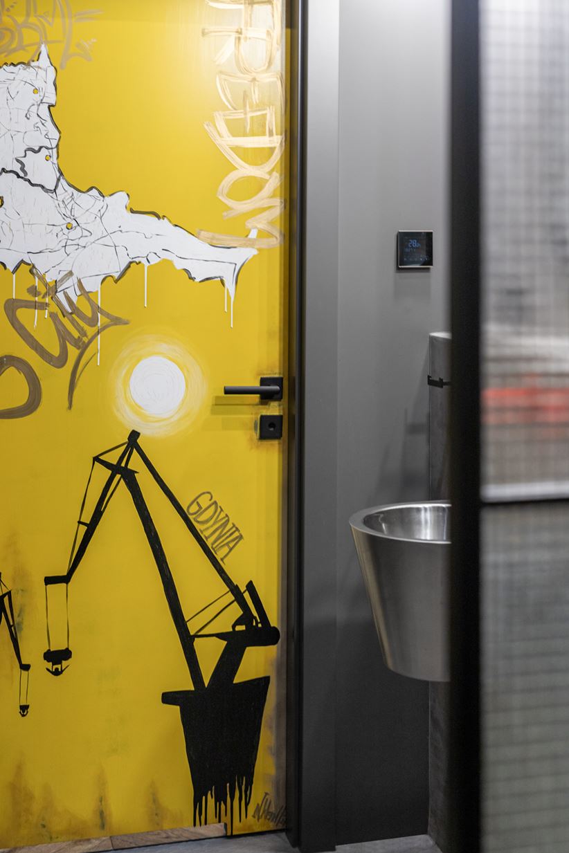 Żółte drzwi łazienkowe ozdobione graffiti